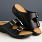 Pair of black sandals with brown soles on a light surface with a dark background